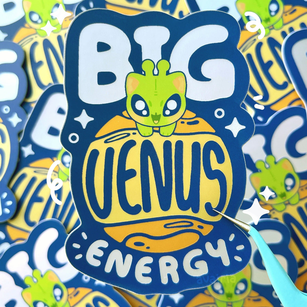 A dark blue sticker with an alien cat riding a planet, there is text behind it, on the planet and below the planet which together read as "BIG VENUS ENERGY". Everything except the dark blue colour have a matte holographic effect.