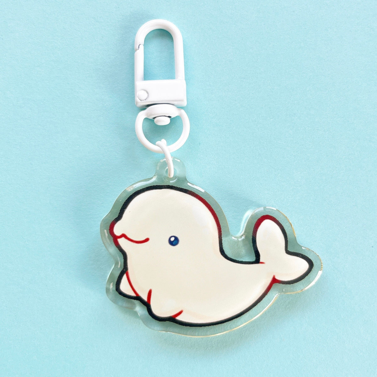 An acrylic charm of a beluga whale, it has a white clasp accessory.