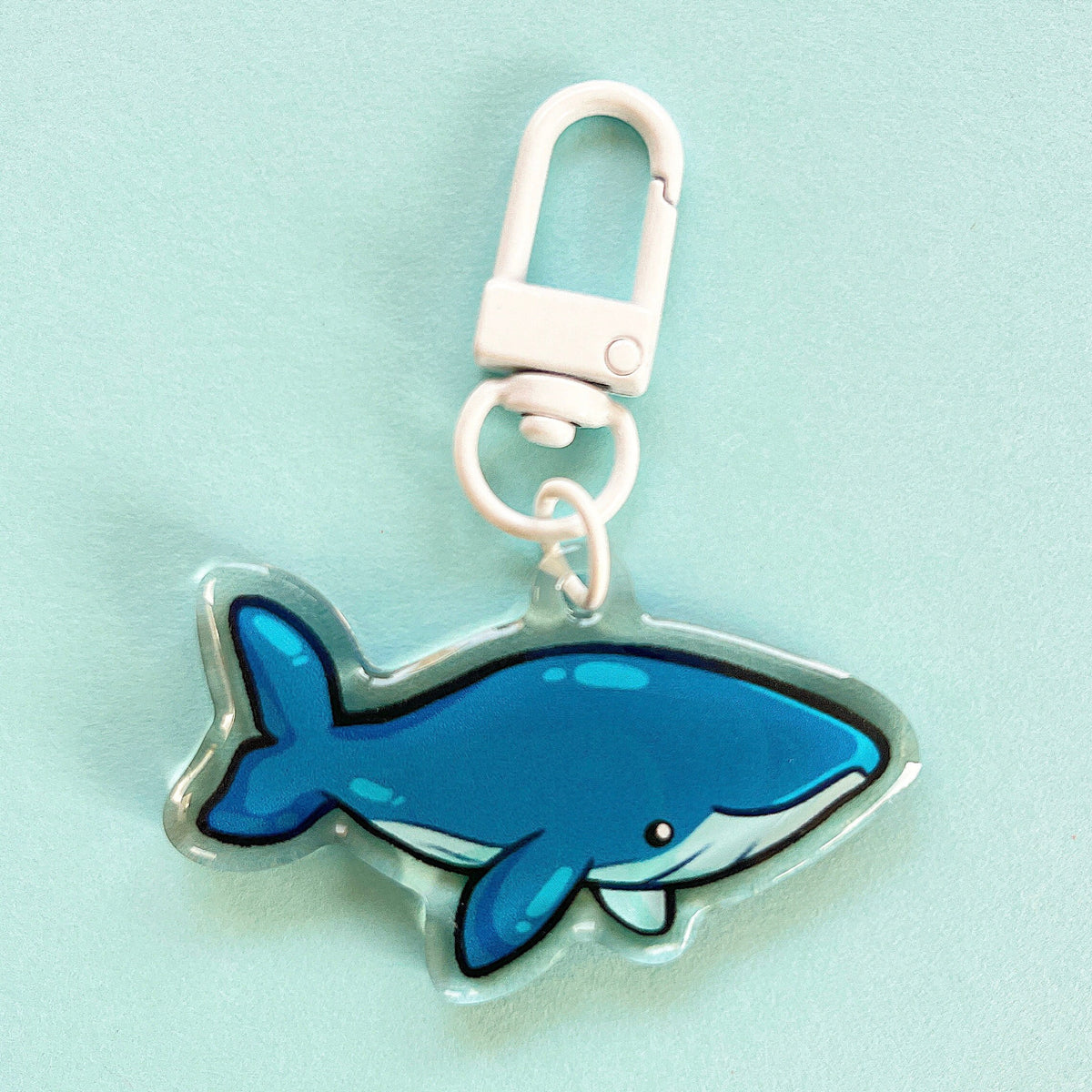 An acrylic charm of a blue whale, it has a white clasp accessory.