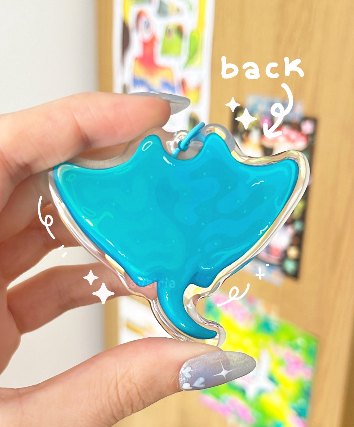 The backside of the charm, which has a different design showing the back of a manta ray. The charm has a blue keychain clip accessory.