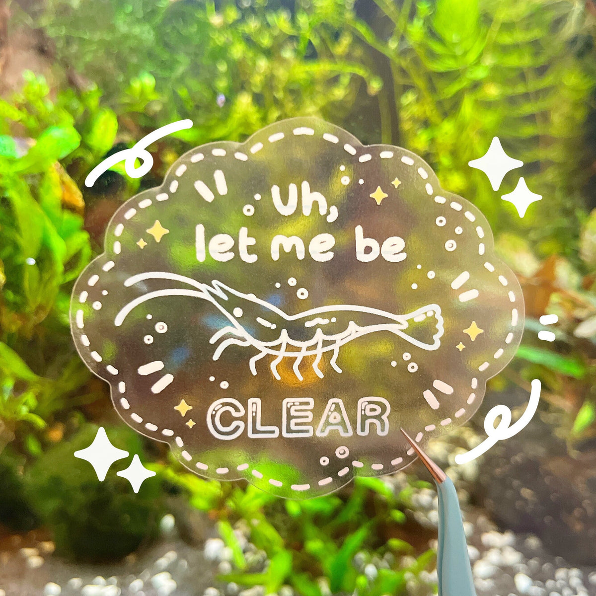A clear sticker with a shrimp at the centre. The sticker has a white dotted border, yellow stars and white effects, and it has white text that reads "Uh, let me be CLEAR".